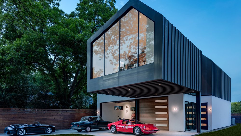A Ferrari 246 GTS, Alfa Romeo Giulia and Porsche custom displayed in the driveway of a small home and large garage envisioned by Texas-based Matt Fajkus Architecture.
