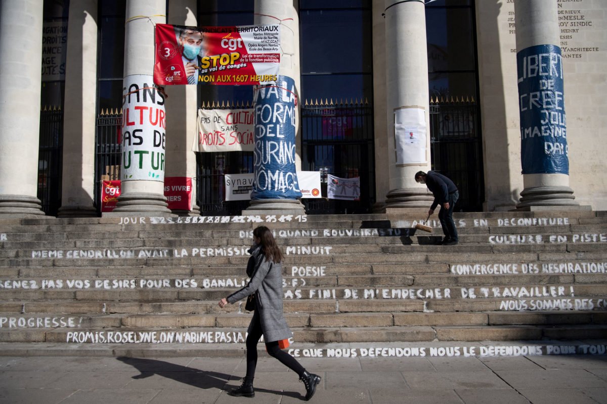 A man cleans the stairs of the occupied Theatre Graslin by culture workers, in Nantes, western France, on March 25, 2021, to demand the reopening of cultural places and theatres, a year after the first closing measures to curb the spread of the Covid-19 (novel coronavirus) pandemic. - They are following the example of the action at the Odeon Theatre, occupied since March 4, 2021 by cultural actors and workers who are demanding the reopening of cultural venues and a financial aid. (Photo by LOIC VENANCE / AFP)