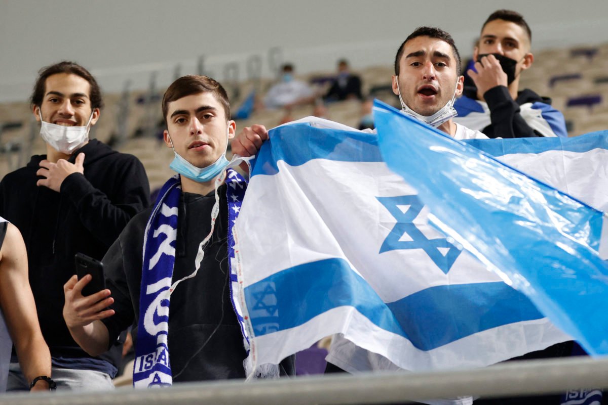 ISraeli fans cheer ahead of the 2022 FIFA World Cup qualifier group F football match between Israel and Denmark at Bloomfield stadium in the Israeli Mediterranean coastal city of Tel Aviv on March 25, 2021. (Photo by JACK GUEZ / AFP)
