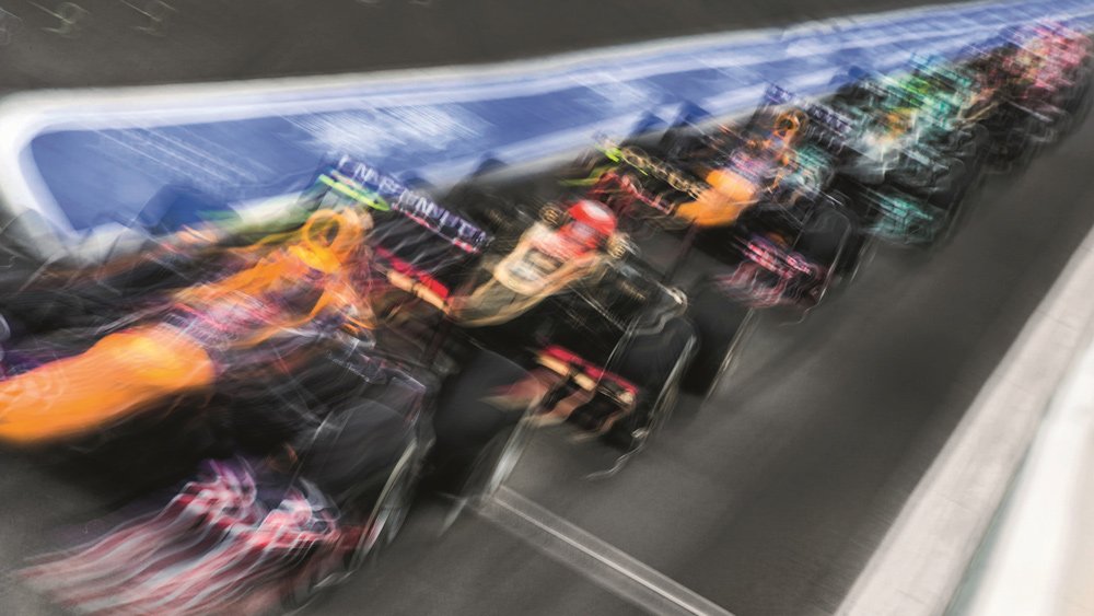 Formula 1 race cars gearing up to exit pit lane.
