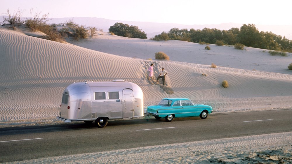 A couple head off the beaten path with their Airstream in tow toward the middle of last century.