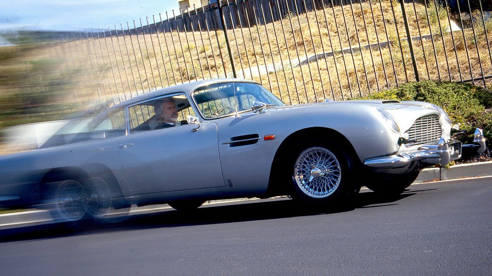 Writer Howard Walker pilots the original Aston Martin DB5 driven by actor Sean Connery in the James Bond film