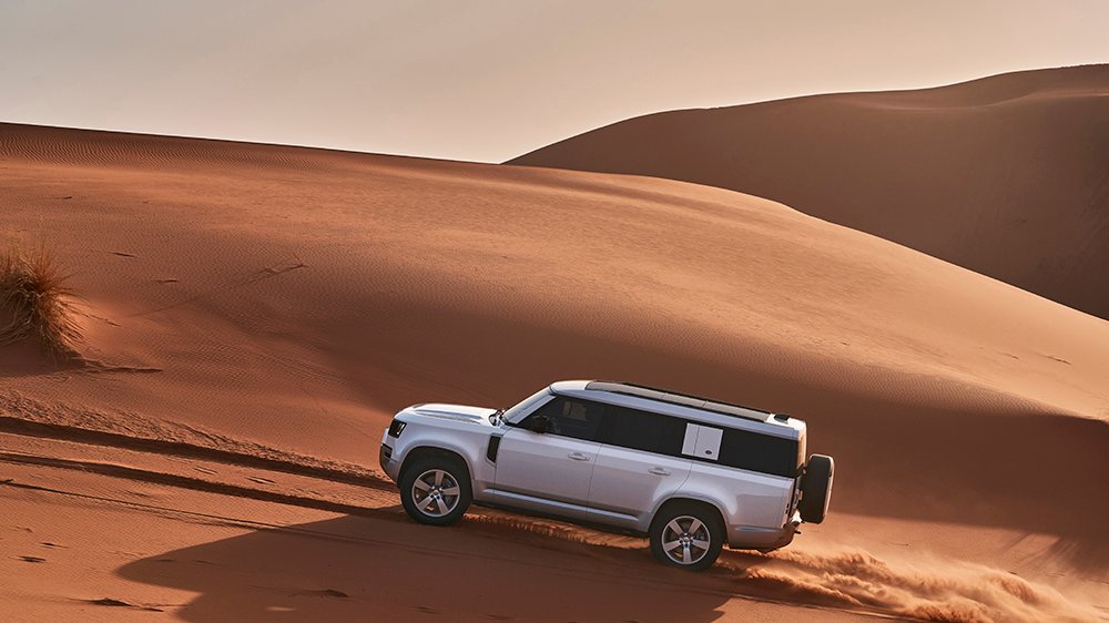 The 2023 Land Rover Defender 130 driving up a dune