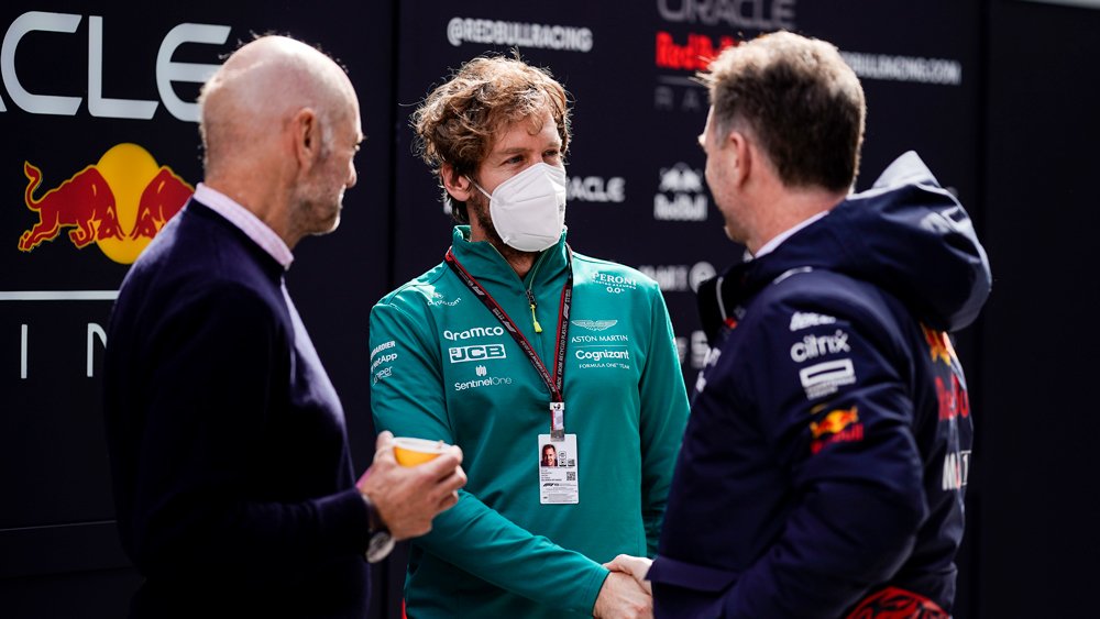 Red Bull Racing's Adrian Newey and Christian Horner (left and right, respectively) greet Formula 1 racer Sebastian Vettel during 2022 pre-season testing.