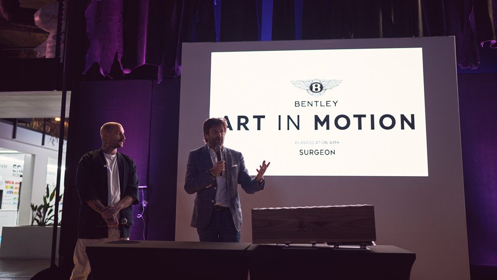 Christophe Georges, president and CEO of Bentley Americas, speaks at the debut of a collaboration between Bentley and the Shoe Surgeon while the latter's founder, Dominic Ciambrone, looks on.