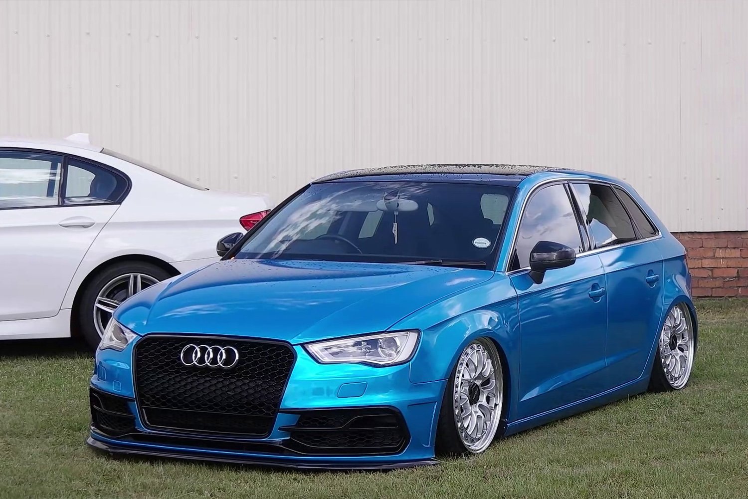 A modified Audi standing on the grass at a car show.