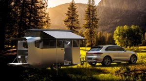 The Airstream Studio F.A. Porsche Concept Travel Trailer and a Porsche Cayenne in a meadow